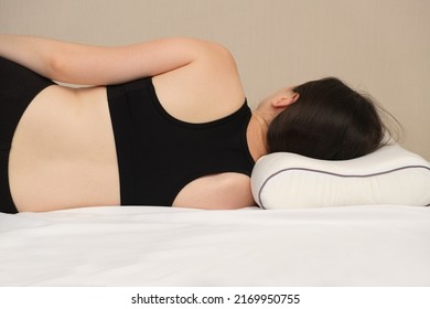 A Woman Lies On An Orthopedic Pillow, View From Behind. Correct Posture And Position Of The Spine During Sleep On The Side.