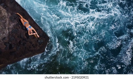 Woman Lies On A Rock, Stones In The Atlantic Ocean. Aerial View Of Crashing Waves On Rocks.