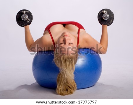 woman lies on stability ball while exercising arms with dumbbells