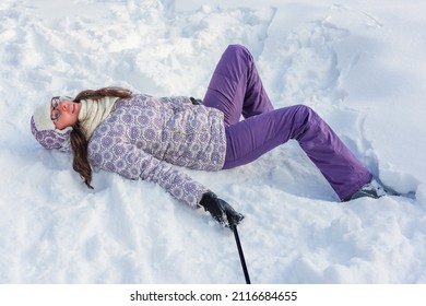 Woman Lies On White Snow After Ski Fall. Contented Emotion On Her Face