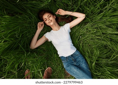 a woman lies in the tall grass with her eyes closed - Shutterstock ID 2279799463