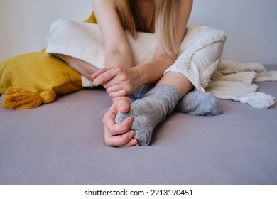 The Woman Lies In Warm Gray Socks In Bed And Covers Herself With A Blanket. Women's Legs In Cozy Socks. View From Above. Warm Evenings At Home