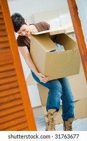 Woman Lifting Cardboard Box While Moving Home, Smiling.