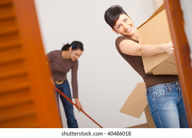 Woman Lifting Cardboard Box While Moving Home, Smiling.