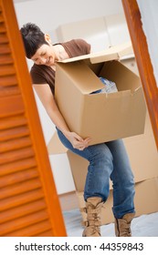 Woman Lifting Cardboard Box While Moving Home, Smiling.