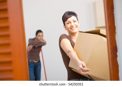 Woman Lifting Cardboard Box While Moving Home, Smiling.