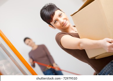 Woman Lifting Cardboard Box While Moving Home, Smiling.?