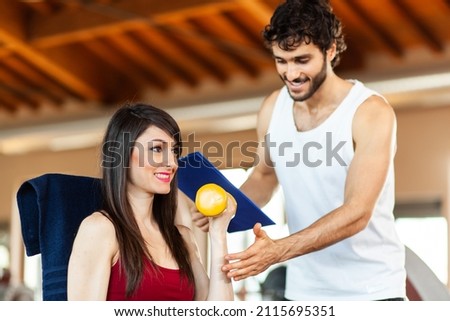 Woman lifting dumbbells with instructor