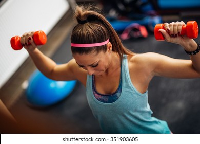 Woman Lifting Weights And Working On Her Shoulders At The Gym