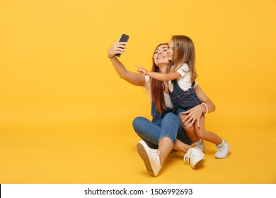 Woman In Light Clothes Doing Selfie With Cute Child Baby Girl 4-5 Years Old. Mommy Little Kid Daughter Isolated On Yellow Background Studio Portrait. Mother's Day Family Parenthood Childhood Concept