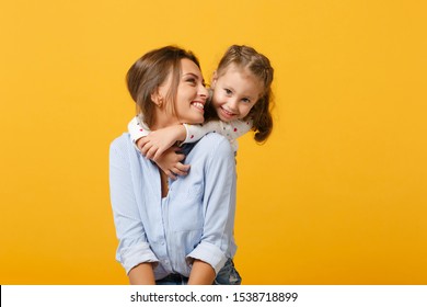 Las mujeres con ropa ligera se divierten con una linda niña de 4 a 5 años. Mamá hija pequeña aislada en un retrato amarillo en el estudio. El Día de la Madre Ama el concepto de la paternidad de la familia