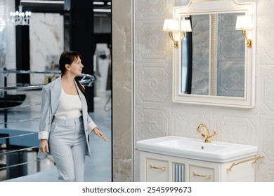 A woman in a light grey suit stands in a modern showroom, looking towards the right side of the frame. A large, white, freestanding bathtub is in the foreground - Powered by Shutterstock