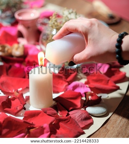 woman lighting a candle over rose petal background. stones, herbs and candles during spiritual practice. magical rituals, spiritualistic and channeling session.