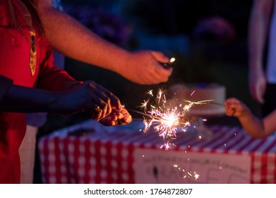 A Woman Is Lighting Sparklers At A Backyard Family Celebration