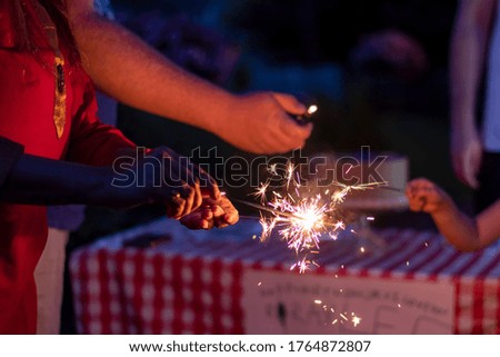 A woman is lighting sparklers at a backyard family celebration