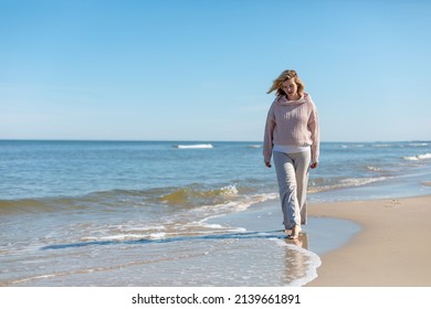 Woman In Linen Trousers Walking Barefoot On Sandy Beach