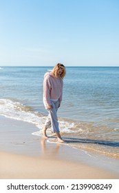 Woman In Linen Trousers Walking Barefoot On Sandy Beach