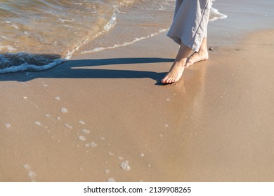 Woman In Linen Trousers Walking Barefoot On Sandy Beach