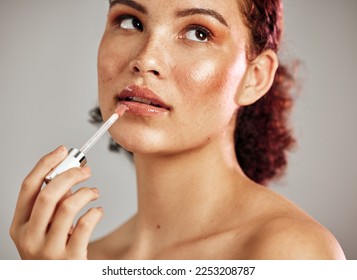 Woman, lips and lipstick application for beauty, cosmetics dermatology and skincare wellness in grey background. Female model, thinking face and lip gloss brush or makeup product for self care - Powered by Shutterstock