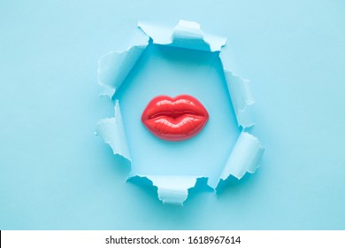 Woman lips with pastel blue torn paper minimal creative kiss and love concept.