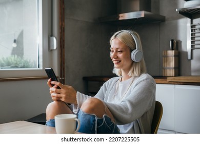 woman listen music on headphones and using smart phone at home - Shutterstock ID 2207225505