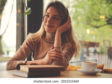 Woman Listening To Audiobook At Table In Cafe