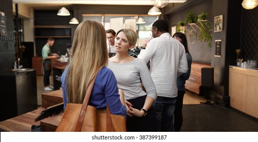 Woman Listening With Concern To Friend In Busy Cafe