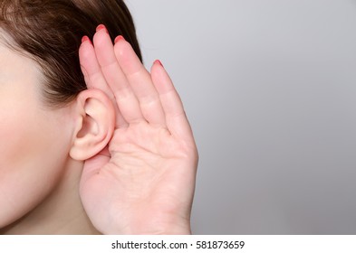 woman is listening with a hand next to her face close up - Shutterstock ID 581873659