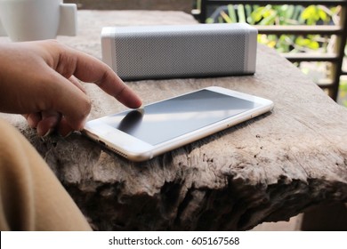 Woman Listening To Music On Bluetooth Speaker With Smart Phone
