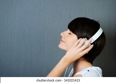 Woman Listening To Music On Earphones With Her Hands To Her Ears And Eyes Closed In Pleasure And Bliss, Profile Head And Shoulders Portrait With Copyspace