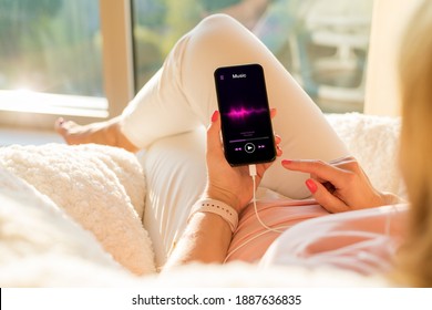 Woman listening to music on mobile phone while relaxing at home