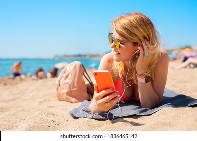 Woman listening to music while relaxing on the beach in hot summer day - Powered by Shutterstock