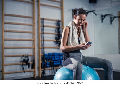 Woman listening to the music while sitting on a exercise ball in the gym. - Powered by Shutterstock