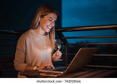 Woman Listening Music While Working On Laptop At Night. High ISO Image.