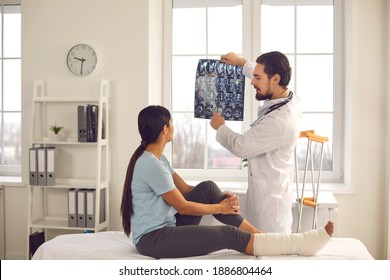 Woman listening to orthopedic doctor at hospital. Trauma surgeon or radiologist talking to patient, showing broken leg or foot fracture X-ray film, explaining treatment course, giving recovery advice - Shutterstock ID 1886804464