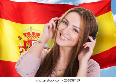 Woman Listening Spanish Learning Audiobook In Front Of Spanish Flag