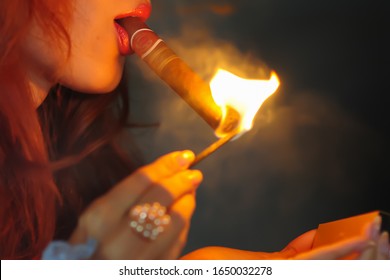 Woman Lit A Match And Lights A Cigar