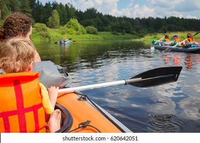 Woman and little boy sail on inflatable boat near two other boats on river at sunny summer day