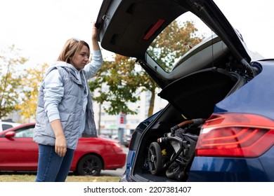 A Woman Loaded A Baby Stroller Into The Trunk Of A Car