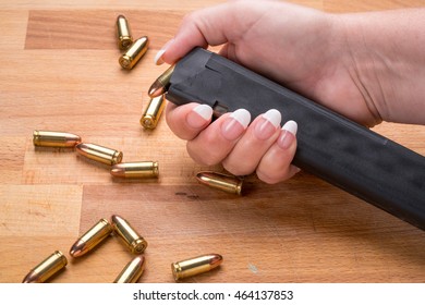 Woman Loading 9mm Ammunition in High Capacity Handgun Magazine on wood Surface