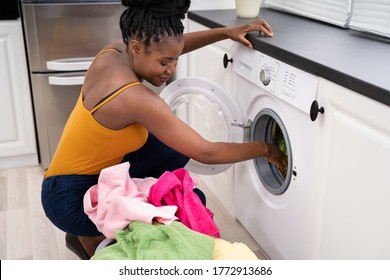 Woman Loading Dirty Clothes In Washing Machine For Washing In Utility Room - Powered by Shutterstock