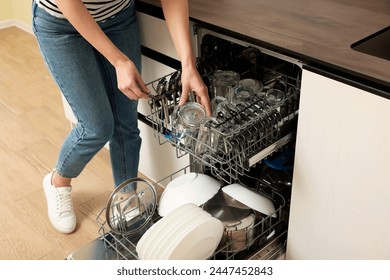 Woman loading dishwasher with glasses and plates, closeup - Powered by Shutterstock