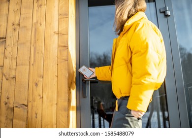 Woman Locking Smartlock On The Entrance Door Using A Smart Phone. Concept Of Using Smart Electronic Locks With Keyless Access