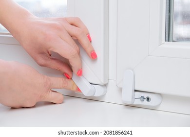 Woman Locks A Child Safety Lock On A Window Frame An Apartment On A High Floor. Security Lock For Windows Ensures The Safety Of Your Children And Prevents Accidents.