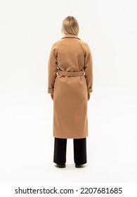 Woman In Long Beige Coat With Belt  On White Background. Warm Coat For Autumn Or Winter. Vertical. Rear View