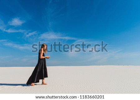 Woman in long black dress with aquarium in desert
