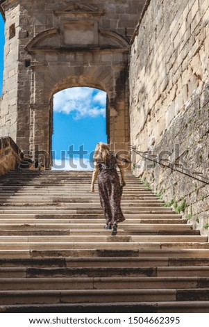 woman in a long dress is climbing the steps of the abbey of Saint Antoine France. concept of tourist destination