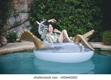 Woman In A Long Dress On The Inflatable Pegasus In The Pool (with Extra Grain, Old Photo Effect)
