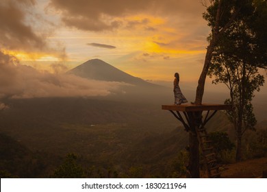 Woman In A Long Dress Stands With Bali Landmark Volcano Agung View. Travel Blogger, Indonesia Best Sunset Point Destination. Woman Retreat. High Quality Photo