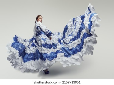 Woman in long fluttering dress with blue and white sea waves. Drawing and ruffles on clothes.                  